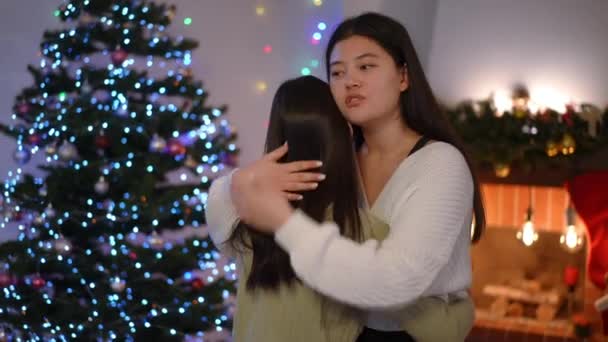 现场摄像头放大到亚洲女人拥抱朋友爱抚发话 圣诞前夕在室内为朋友代言的年轻爱心女子的画像 — 图库视频影像