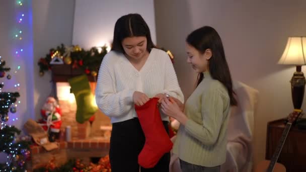 Two Happy Asian Women Christmas Stocking Talking Taking Candies Mandarins — Stock Video