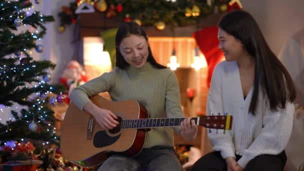 Δύο Ταλαντούχες Ασιάτισσες Που Παίζουν Κιθάρα Τραγουδώντας Χριστουγεννιάτικα Κάλαντα Καθισμένες — Αρχείο Βίντεο