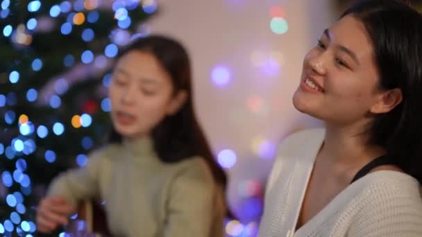 Вид Сбоку Радостная Азиатка Поет Рождественскую Колядку Размытым Другом Играющим — стоковое видео