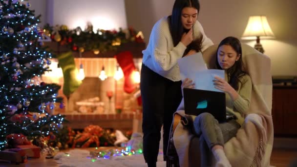 新年前夕 两位专注的亚洲年轻女性坐在客厅里 分析着带着笔记本电脑的文书工作 专心致志的自由职业者计划在右边的室内过圣诞节 慢动作 — 图库视频影像