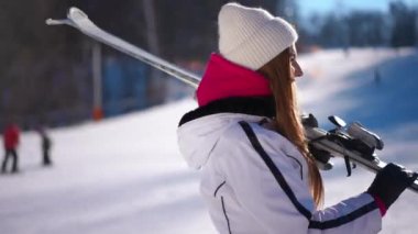 Güneşli kış gününde kayaklarla gezen kendinden emin bir kadının yan görüntüsü. Kafkasyalı mutlu esmer kadın teçhizatla geziyor.