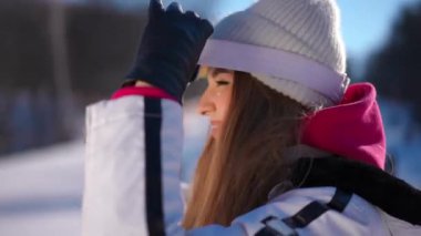 Yan plan, kendine güveni tam, kayak gözlüğü takan, kış tatilinde gün ışığında gülümseyen bir kadın. Açık havada tatil yapan neşeli, beyaz bir bayan. Sağlıklı yaşam tarzı ve spor anlayışı