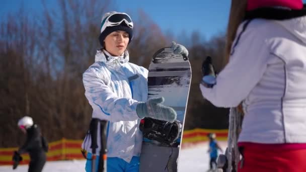 自信を持ってフィットの肖像より良い冬のスポーツについて友人と議論白人のスポーツ女性 スリム美しい若い女性の話ジェスチャー議論スノーボードとスキー上のリゾート晴れた日 — ストック動画
