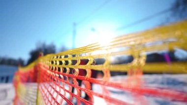 Açık havada güneş gören kayak merkezinin kırmızı ve sarı çitleri. Kış mevsiminde güvenlik sınırı. Gün ışığında gölgeler yavaş çekimde geçiyor.
