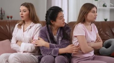 Genç Asyalı bir kadın, beyaz arkadaşlarıyla konuşup bayanları barış yapmaya zorluyordu. Pijamalarıyla kanepede oturan, el kol hareketleriyle gülümseyen mutlu kadın.