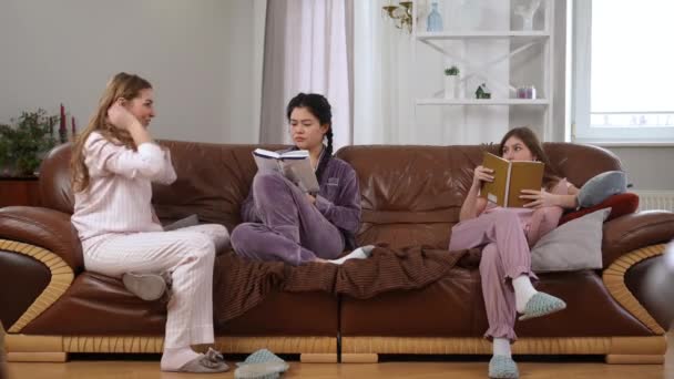 兴奋的年轻女人走进客厅 与书呆子朋友聊天看书 带着嘲讽的表情离去 白种人和亚洲人生活在一起 享受着兴趣爱好 — 图库视频影像