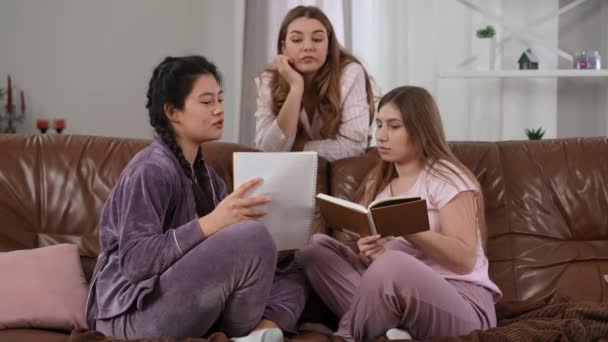 Charming Asian Caucasian Women Sitting Couch Pajamas Discussing Studies Bored — Stock Video