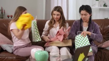 Oturma odasındaki kanepede oturmuş, Kara Cuma alışverişi için savaşan genç kadınlar tartışıyorlar. Üç Kafkasyalı ve Asyalı arkadaş yeni elbiseler giyip konuşuyor. Moda ve kadınlık kavramı
