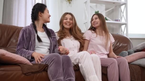 Neşeli Genç Arkadaşlar Dizlerinin Üstüne Çöküp Gülüyor Kanepede Pijamalarıyla Oturuyor — Stok video