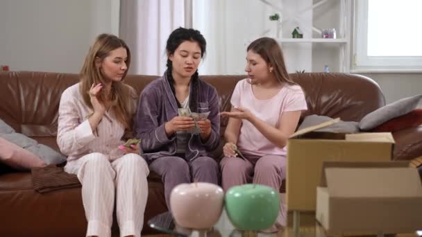Genç Kadın Oturma Odasındaki Kanepede Pijamalarıyla Oturmuş Para Sayarak Gülümsüyor — Stok video