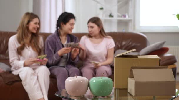 거실에 장식용 사과와 상자를 클로즈업하고 배경에 현금을 아시아 코카서스 여성들이 — 비디오