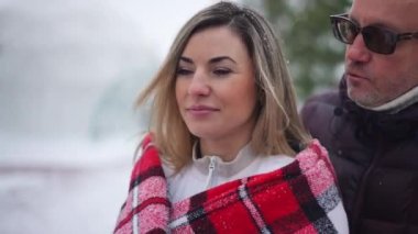 Karlı kış günlerinde yakın plan gülümseyen bir kadın ve gözlerini kapatan bir adam şaşırtıcı bir eş. Minnettar, heyecanlı, mutlu, beyaz, sarılan kadın kocası konuşuyor.