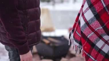 Yanan şenlik ateşinde soğuk kış gününde el ele tutuşan tanınmayan bir çift. Sevgililer Günü 'nde açık havada çıkan beyaz bir erkek ve kadın.