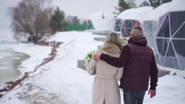 Powrót Widok Kochający Para Dorosłych Spacerujących Bukietem Kwiatów Śnieżny Dzień — Wideo stockowe