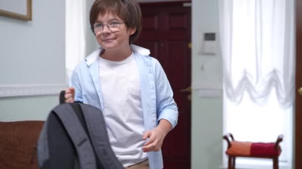 满意的可爱男孩 背着背包走着 手放在脑后 描绘了一个快乐自信的白人学童放学后在家里笑的形象 智力和生活方式 — 图库视频影像