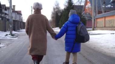 Arkadan bakıldığında, beyaz anne ve oğlunun kış günü sokakta el ele dolaştığından emin. Mutlu bir kadın ve çocuğun okuldan sonra eve giderken çekilmiş resimlerini izliyorum.