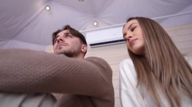 Genç bir kadının bir erkekle flört edişinin alt açısı. Kafasını omzuna koyması, kadını iten adam gibi. Yatak odasında oturan, sevmeyen beyaz bir çiftin portresi.