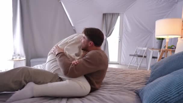 快乐快乐的年轻夫妇依偎在床上放声大笑 爱白种人的男友和女友在室内玩乐的侧视图肖像 幸福与爱情概念 — 图库视频影像
