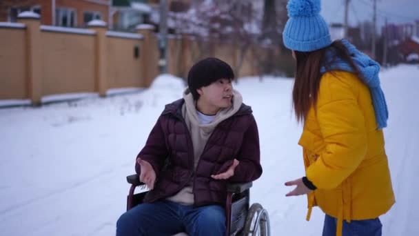 車椅子のアジア系男性は白人女性を女性として歩き去ると言い争っている 悲しいです落ち込んでボーイフレンドQuarrelingとともにガールフレンドとともに冬の日屋外 — ストック動画