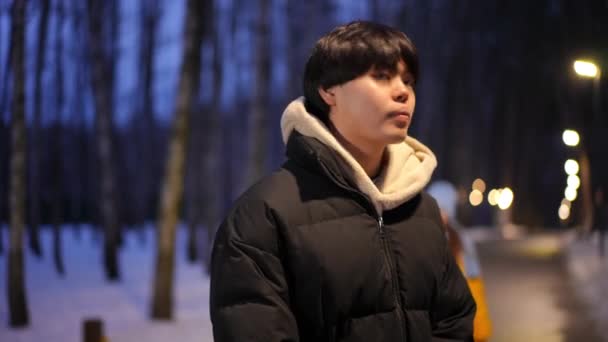 冬の夜に公園に立っている若いアジア人男性は 白人女性が抱擁するパートナーを待っています 笑顔幸せな愛情カップル日付屋外で話して残します — ストック動画