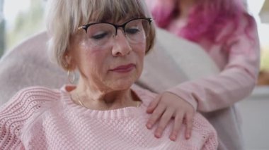 Depresyondaki son sınıf beyaz kadının yakın plan portresi. Çocuk eli omzuna dokunurken iç çekiyor. Evde torununun olduğunu düşünen üzgün yaşlı bir büyükanne.