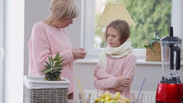 Starsza Kobieta Rozmawia Chorą Słodką Dziewczyną Oferując Tabletki Stojące Kuchni — Wideo stockowe