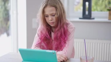Güzel kız dijital tablette online film izlerken şaşırmış yüz ifadesini gülümsetiyor. Kafkasyalı kaygısız kız hafta sonu evde filmle eğleniyor.