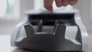 Ön cephedeki para sayma cihazı beyaz erkek el ile başlama düğmesine basıyor. Yüz dolarlık banknotları yakından hesaplayan tanınmayan bir adam.