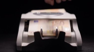 Ön manzara banknot sayacı, erkek el sıkışması başlangıç ve Euro para sayımı. Avrupa nakit paralarını karanlıkta siyah arka planda sayan yakın plan bir cihaz. Para aklama ve kriz