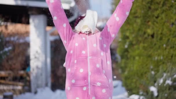 镜头前 一个快乐可爱的高加索女孩微笑着 慢镜头下扔着白雪 中镜头的自信快乐的孩子在后院的户外摆出有趣的姿势 — 图库视频影像