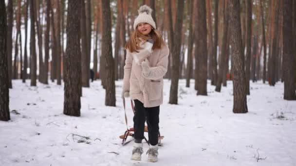 迷人的少女在白雪上慢动作地跑着 拉着雪橇离去 快乐兴奋的高加索美丽少年在度假时享受休闲的正面肖像 — 图库视频影像