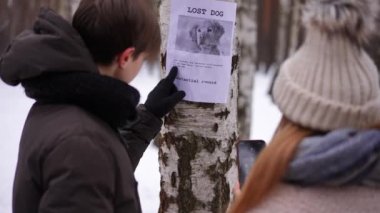 Ağaçtaki kayıp köpek ile ilgili bir duyuru. Genç arkadaşlar kış günü dışarıda bekleyen numarayı arıyor. Bulanık beyaz bir erkek ve kızın omzundan ateş ederek evcil hayvanı bulmaya yardım ediyorlar.