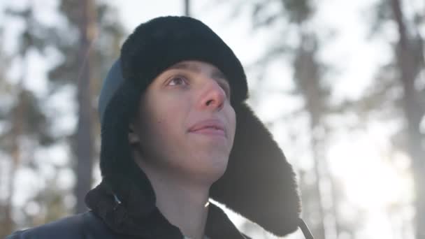 Aufgeregter Unbeschwerter Junger Mann Der Lächelnd Sonnenlicht Winterwald Steht Porträt — Stockvideo
