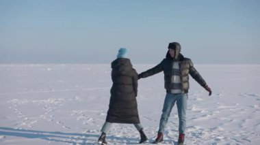 Geniş açılı neşeli karı koca kış çayırlarında karda dans ediyorlar. Sevgi dolu, mutlu beyaz erkek ve kadın eko turizmin tadını çıkarıyorlar. Yavaş çekim