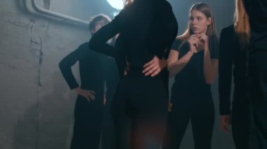 Kuliste sahne arkası ışıklandırması ve performans bekleyen genç kadın ve erkekler var. Endişeli beyaz aktrisler ve aktörler tiyatroda prova yapmaya hazırlanıyorlar.