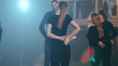 Genç erkekler ve kadınlar sahnede arkadan ışıklandırma ile ısınmak için boyun kaslarını esnetiyorlar. Konsantre Kafkasyalı yetenekli oyuncular ve aktrisler sahne arkasında performans prova ediyorlar.