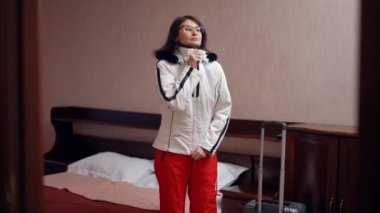 Kendine güvenen, olgun, fermuarlı, kış kıyafetleri giyen seyahat çantası taşıyan bir kadın otel odasından ayrılıyor. Çekici beyaz kadın turistin portresi. Kış tatilinde valizli.