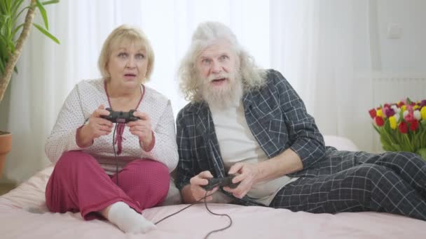 Obekymmersfri Senior Kaukasiska Par Spel Med Joysticks Liggande Sängen Hemma — Stockvideo
