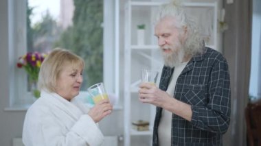 Üst düzey pozitif çift evde duran sağlıklı, lezzetli, muzlu smoothie içiyor. Kendine güvenen Kafkasyalı karı-koca sabah içkilerinizi yudumlarken gülümseyin.