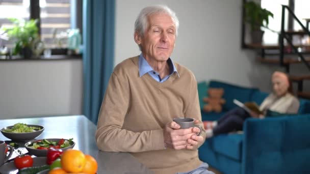 Thoughtful Smiling Senior Man Drinking Coffee Dreaming Blurred Woman Reading — Vídeo de Stock
