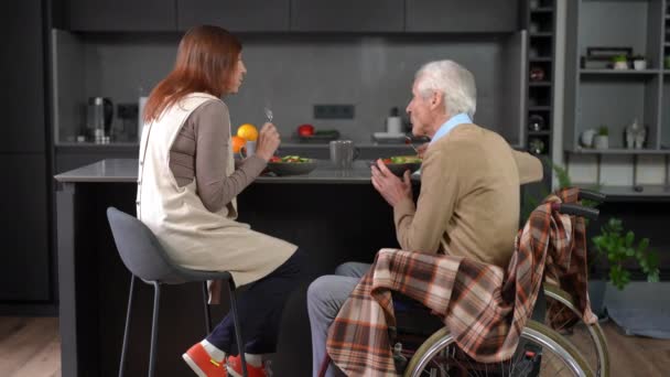坐在轮椅上与丈夫共进午餐的积极老年妻子的后视镜 自信的白种人夫妇享受着与人聊天的快乐 — 图库视频影像