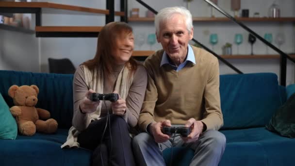 Carefree Joyful Couple Retirees Gaming Game Controllers Smiling Talking Sitting — Stok video