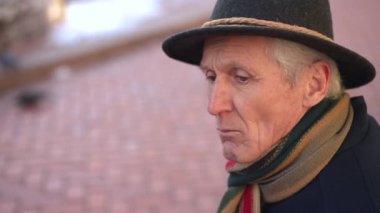 Side view headshot of depressed senior man sitting on city street on the right thinking. Frustrated Caucasian lonely male retiree outdoors on spring autumn day