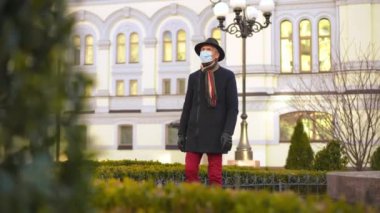 Portrait of senior Caucasian man in coronavirus face mask walking on city street leaving. Elegant male retiree strolling outdoors on Covid-19 pandemic outbreak on spring autumn day