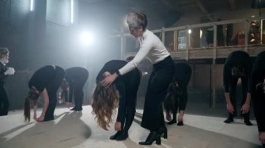 Positive talented actors and actresses standing up raising bodies slowly smiling rehearsing performance on backstage. Professional theater director leading rehearsal talking helping men and women