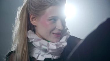 Headshot of smiling talented theater actress in neck ruff talking standing in backlit on backstage. Close-up portrait of joyful Caucasian beautiful slim woman getting ready for performance