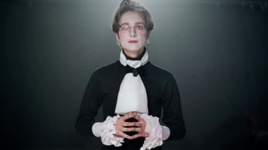 Actor in costume with stage makeup playing role waking up looking around talking with curios facial expression and falling asleep. Front view portrait of young talented Caucasian man posing on stage