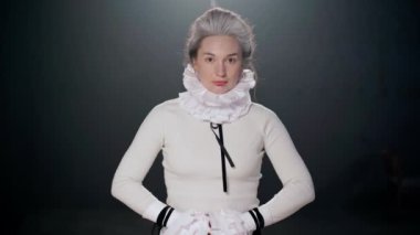 Confident gorgeous actress looking at camera gesturing with hands and looking down. Portrait of talented beautiful Caucasian woman playing on stage posing in theater indoors