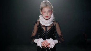 Beautiful Caucasian young actress looking at camera imitating orchestrate standing on stage in theater. Portrait of confident talented woman posing smiling performing role playing